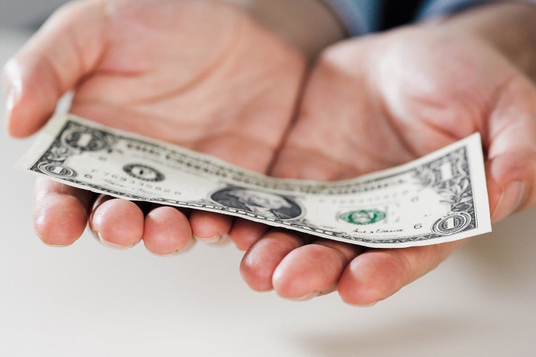 A pair of hands presents a single dollar bill.